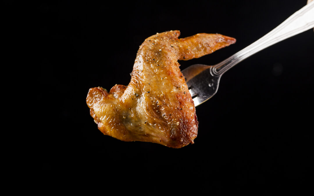 La carne di pollo fra le star risulta molto in voga negli ultimi tempi: tanto da esser diventata uno degli elementi principali della loro dieta. In questa foto un'aletta di pollo piccante raccolta con una forchetta.