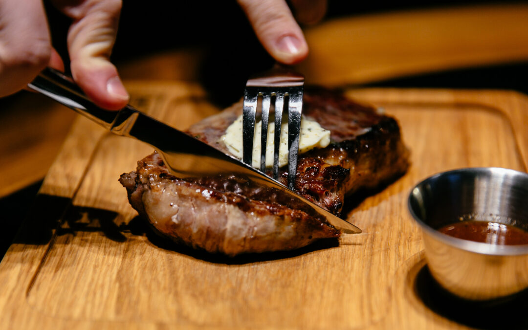 Qual è il grado di cottura migliore della carne? Nella foto un uomo che gusta una bistecca.