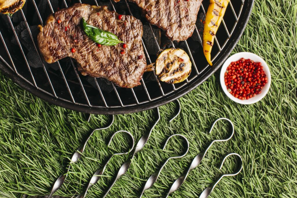 Se ci chiediamo come cucinare carne in estate, il segreto sta nella sperimentazione. Tante le ricette: da quelle fredde a quelle con carne raffreddata da servire a temperatura ambiente. Nella foto della carne alla griglia vista dall'alto in un prato.